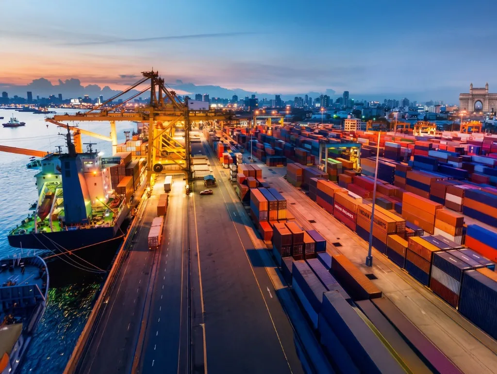 Port terminal with cargo ship, containers and crane at dusk